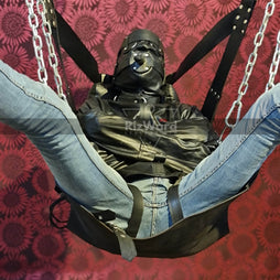 a person wearing a strait jacket and hood sitting on sex sling while opening his legs - sex sling and swing